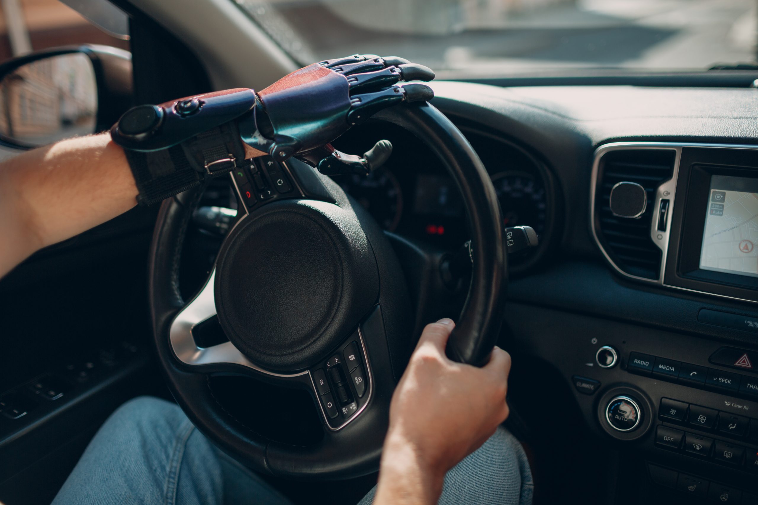 Young disabled man driver with artificial prosthetic hand driving vehicle car. disabled